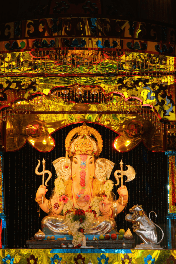 Devotees offering prayers before a large decorated Lord Ganesha idol during Ganesh Chaturthi festival